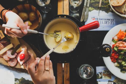 People dipping potatoes into cheese fondue