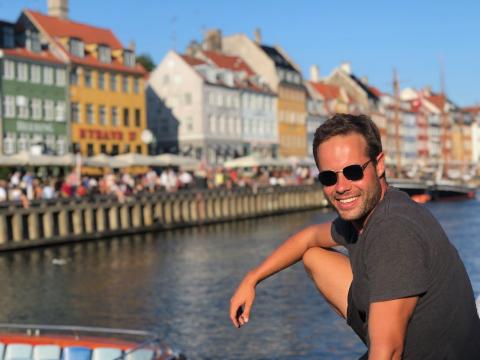 A man standing by bright coloured houses and lake in Copenhagen