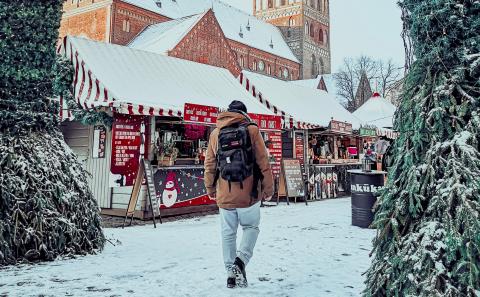 A man walking past Christmas markets in the snow