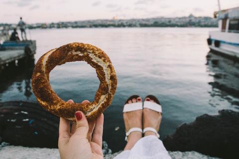A woman holding a Simit, which is somewhere between a pretzel and a bagel
