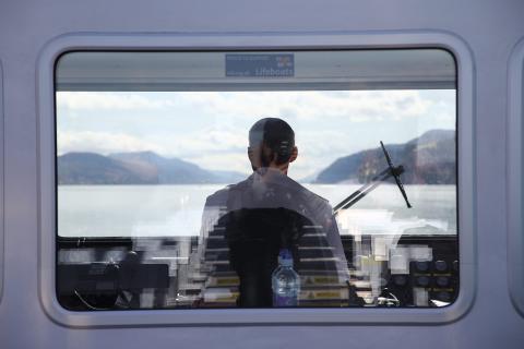Looking through a window to see the back of a boat driver 