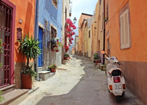 A street in Italy with colorful houses and a vespa