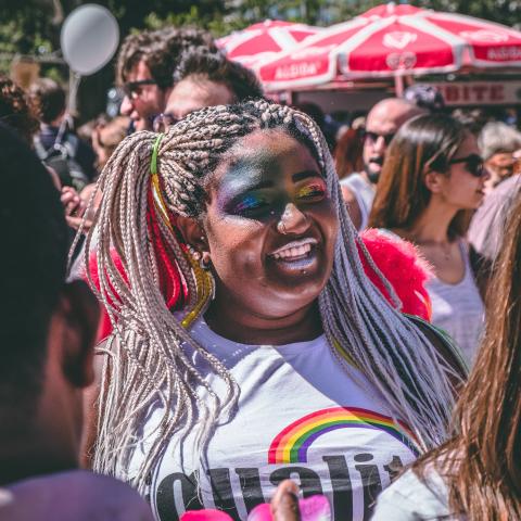 A woman in the pride parade. Her face is covered in colourful glitter