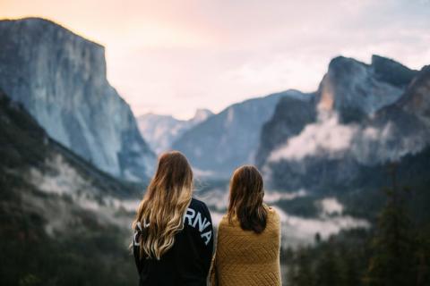 two women with their backs to the camera staring at mountains