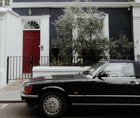 A black car parked in front of a house with a red door