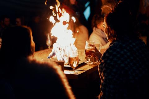 People drinking beers around a fireplace in a pub