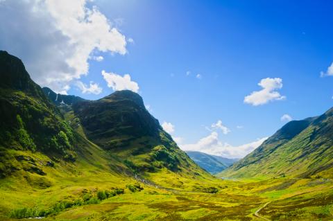 Green Scottish mountains and a bright blue sky