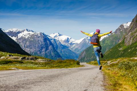 a person jumping on a road with Swiss mountains in the back
