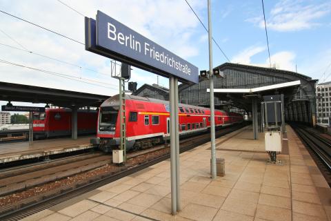 A red train pulling into Friedrichstrasse Railway Station