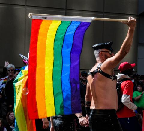 A man holding a large pride flag
