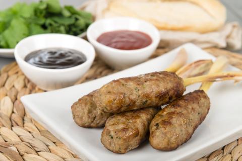 A plate of a pork skewer and dips