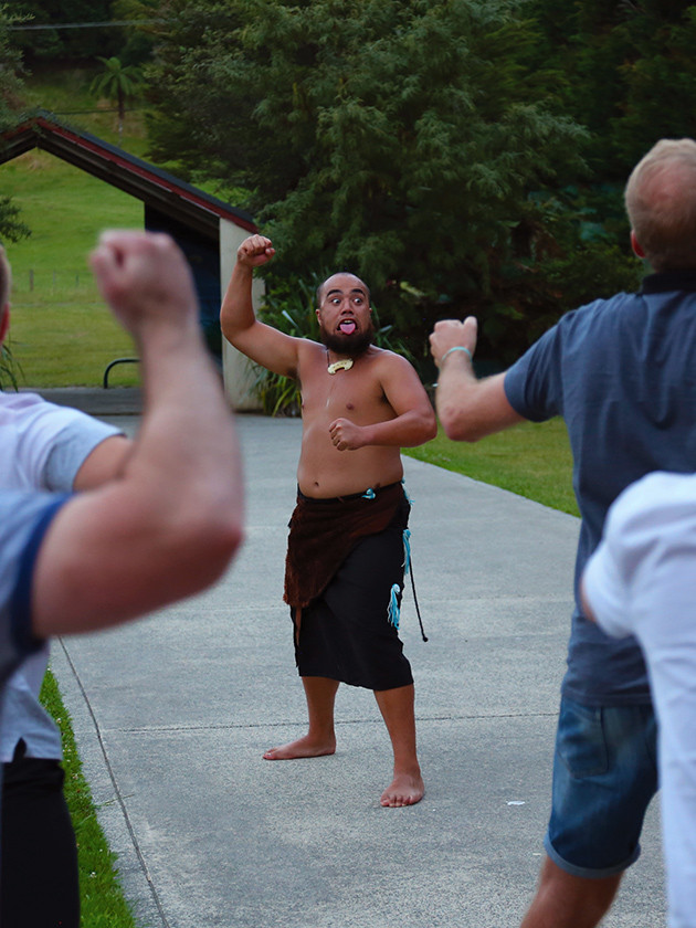 Maori guide teaching war cries to Topdeck tour group in New Zealand.