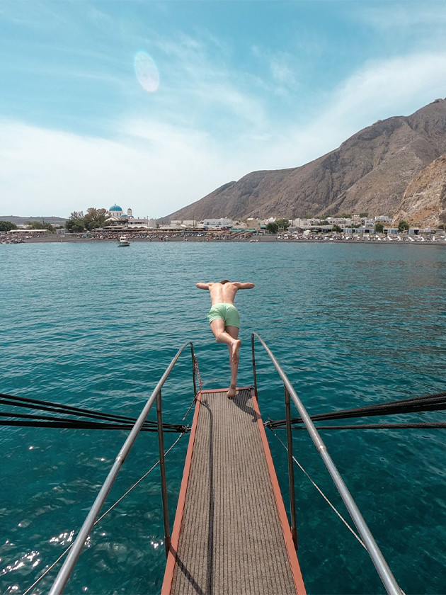 Man at the end of a boat sailing through the Greek Islands.