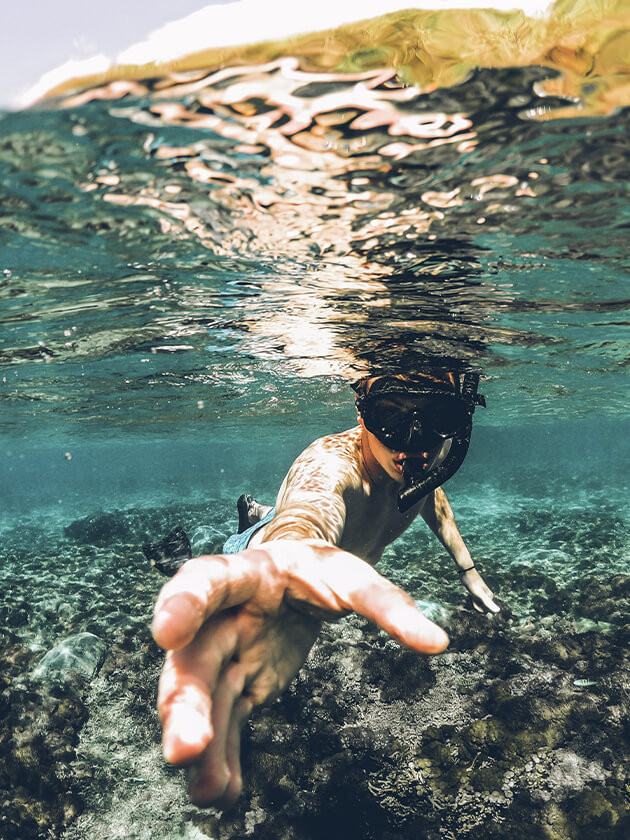 Topdeck traveler grabbing a rock while swimming in the seas surrounding Bali.