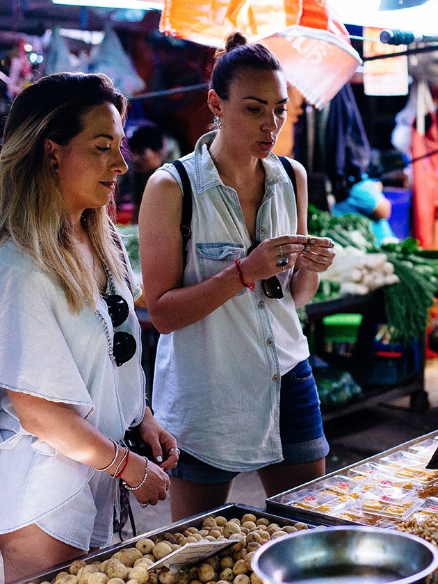 Topdeck travelers browsing Thai spice market.