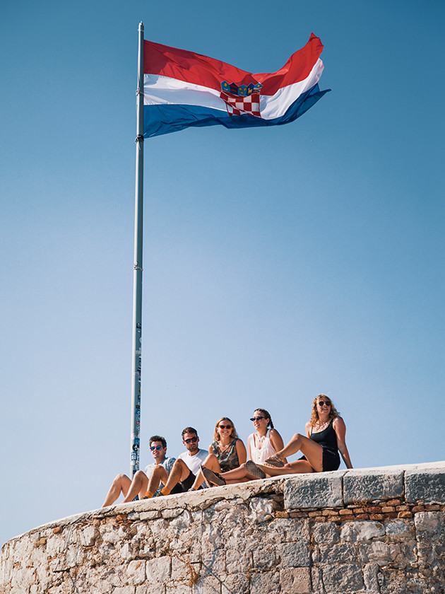 People posing underneath the Croatian flag at Hvar Fortress.