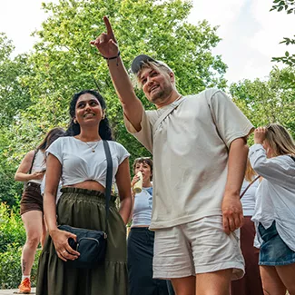 Two people standing beside each other, with one pointing to the left.