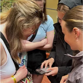 Group of people looking down at a phone together.