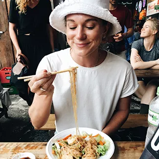 Person holding up noodles from a bowl with chopsticks.