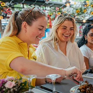 Person seated at a table picks up escargot from a plate with tongs.