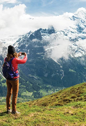 Person taking a photo of a mountain with snow.