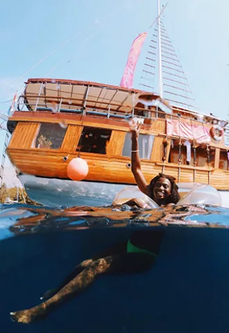 Person floating in an inflatable ring next to a sail boat in Croatia.