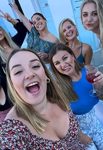 People smiling together for a photo in a white street on a Greek Island.
