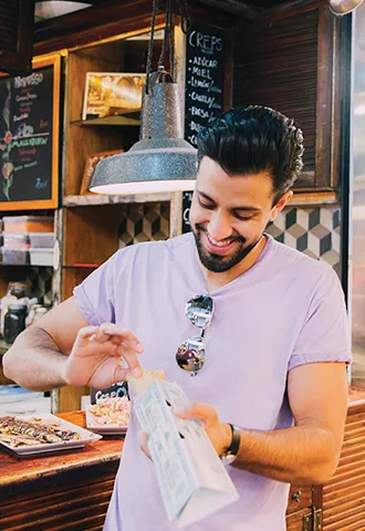 Person holds some type of street food within a cardboard carry container.