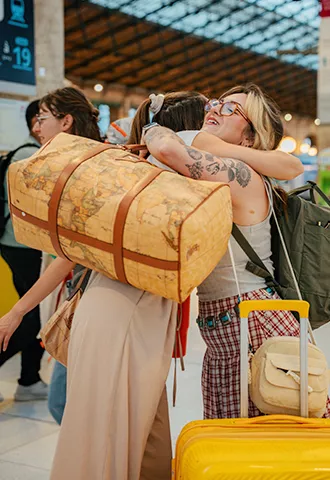 People holding luggage hug each other at a train station in Paris.