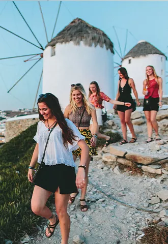 People walking down a path next to the Windmills of Mykonos.