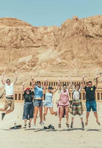 Group of people jumping in front of an ancient monument.