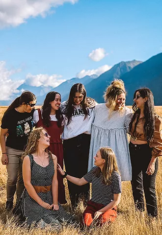 People standing together for a photo in dry grass within a valley.