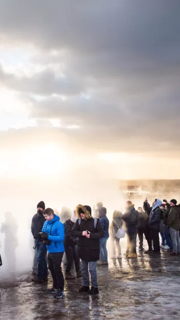 Group of people standing in steam produced by geothermal activity.
