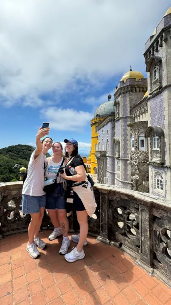 Topdeck travelers taking a selfie together in front of the famous National Palace of Pena in Sintra.