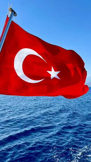 Turkish flag blowing in the wind over the ocean.