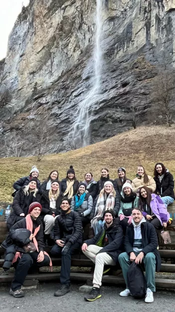 A Topdeck travel group posing for a photo together in front of the Staubbach Falls in Switzerland.