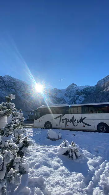 A Topdeck tour bus is parked at a snow covered ski-resort in the Swiss Alps.