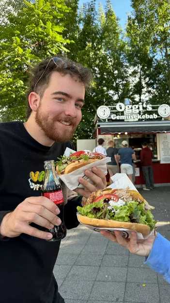 Guy holding a doner kebab and a bottle of Coke in Berlin, Germany.