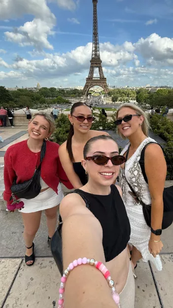 Four people smiling together in front of the Eiffel Tower in Paris.