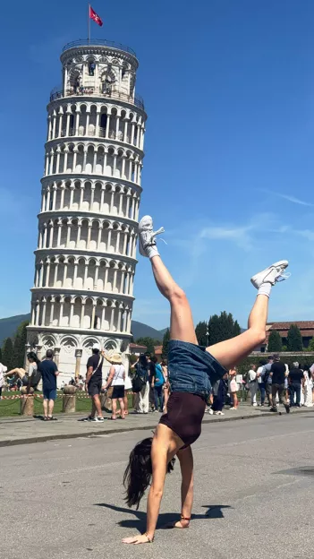  Person does a hand-stand in front of the Leaning Tower of Pisa.
