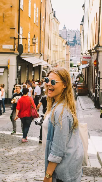 Person wearing sunglasses turning and smiling.