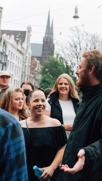 Group of people listening to a man speak on the streets of a European city.
