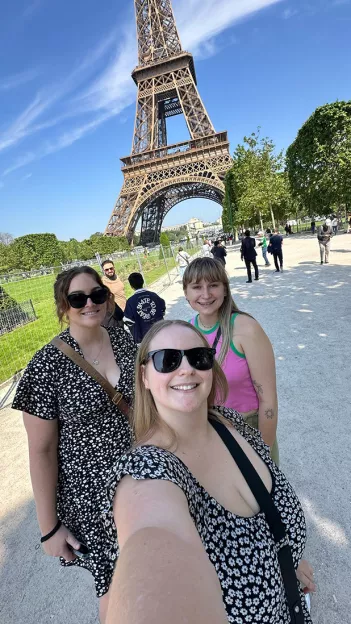 Three Topdeck travelers posing for a selfie in front of the Eiffel Tower.