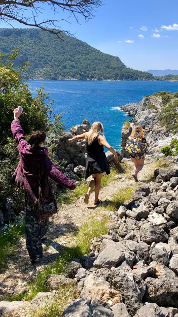 People walking down a coastal pathway with the ocean to their left.
