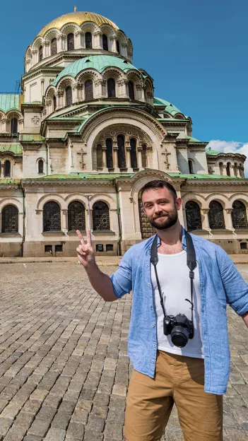 Person with a camera hanging around their neck standing in front of the Alexander Nevsky Cathedral in Sofia, Bulgaria.