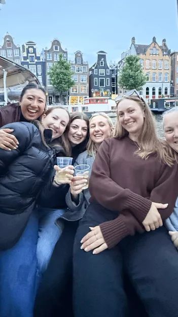 Six people sitting up against each on a canal boat in Amsterdam.