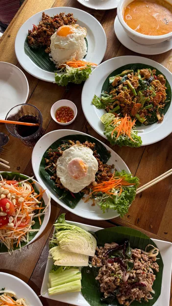 Full spread of Thai dishes with rice, egg, various vegetables and sauces together on a table.