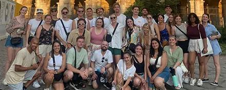 Topdeck Tour group posing for a photo in front of the famous Colosseum of Rome.