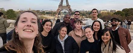 A Topdeck Tour group taking a group picture in front of the Eiffel Tower in Paris.