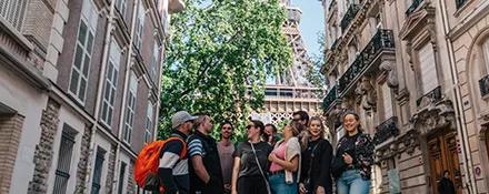 Topdeck travellers strolling through the streets of Paris, with the Eiffel Tower in the background.